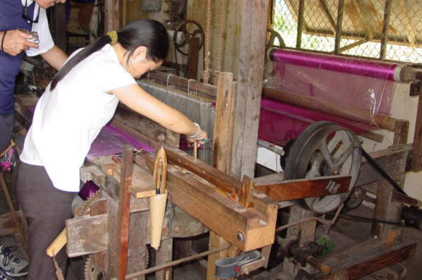 Asian woman working on a large loom