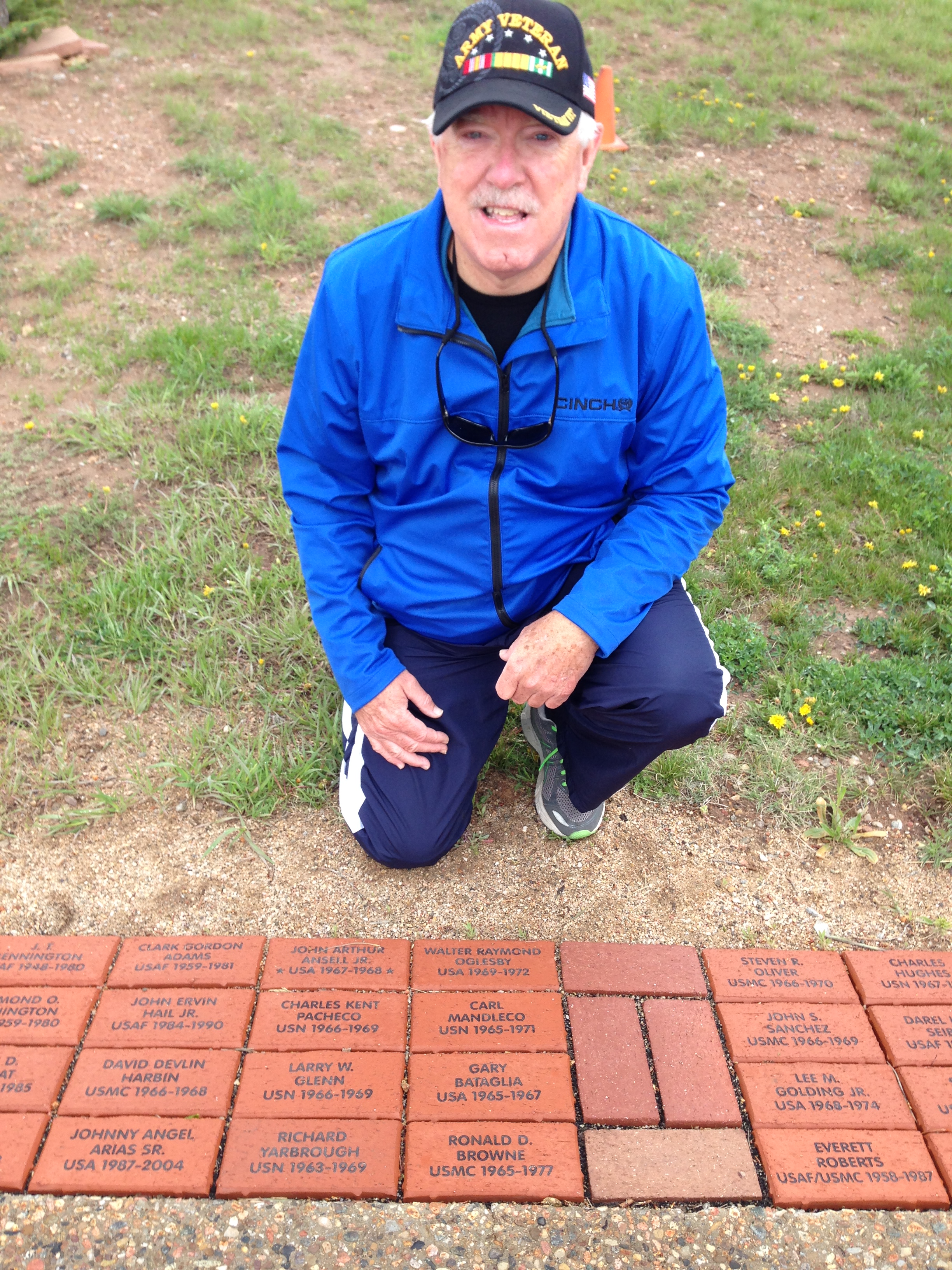 Army veteran kneeling by inscribed bricks