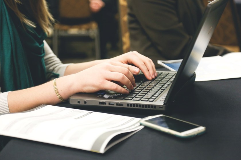 a woman's hands typing on a laptop keyboard