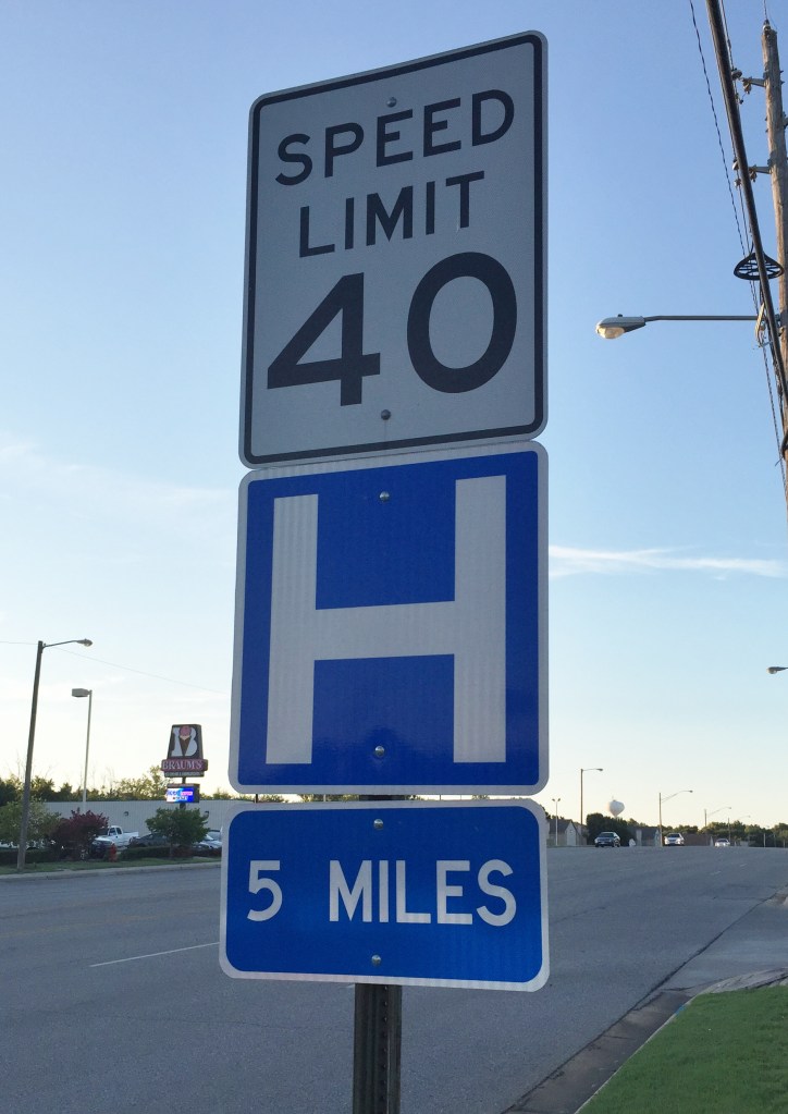 a speed limit sign with an H for hospital , 5 miles