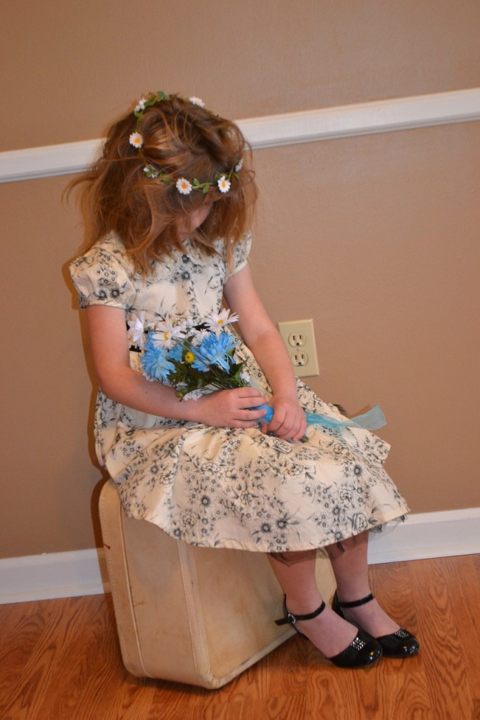 a little girl sitting, holding a bouquet of flowers