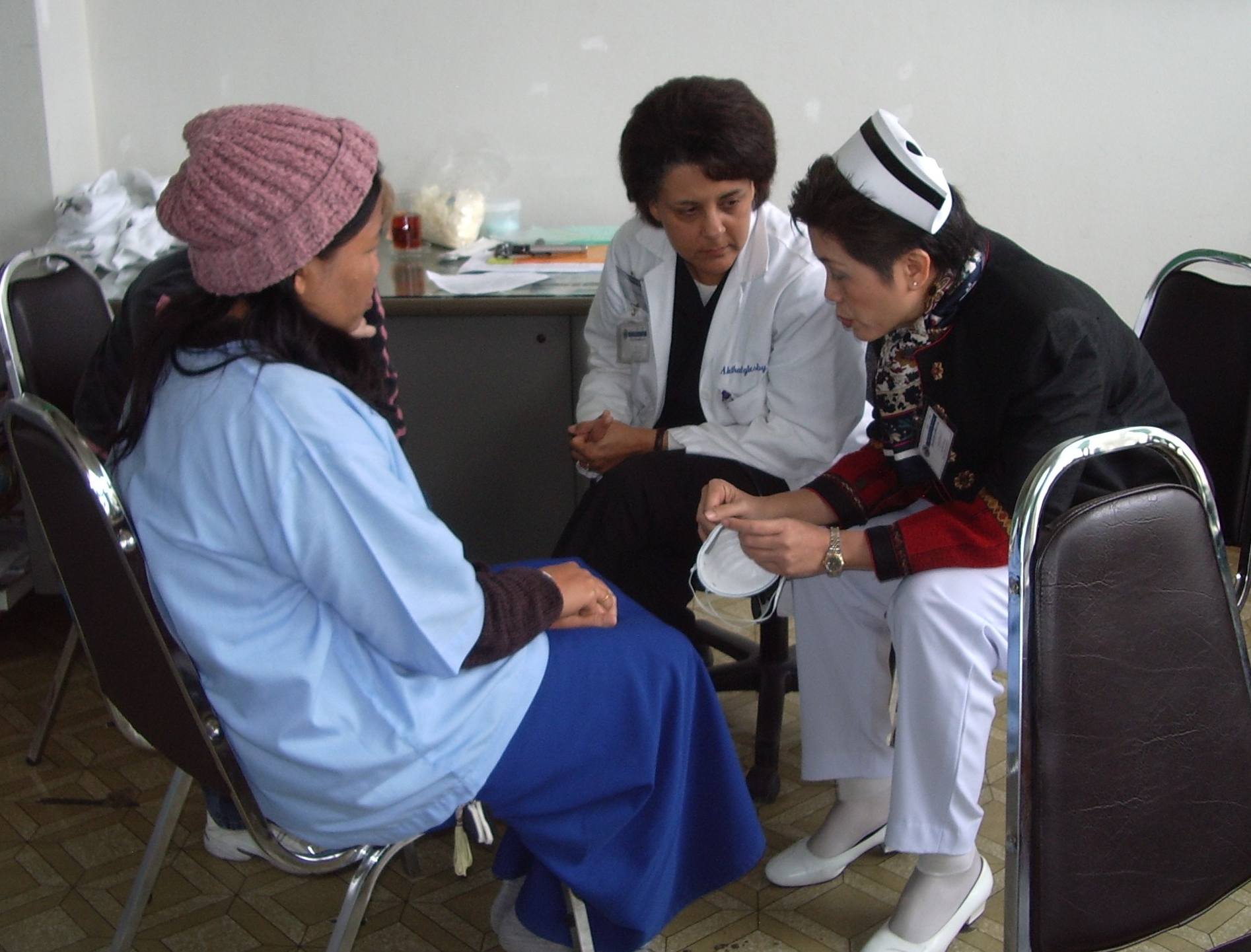 a doctor and nurse talk to a patient in an Asian country.