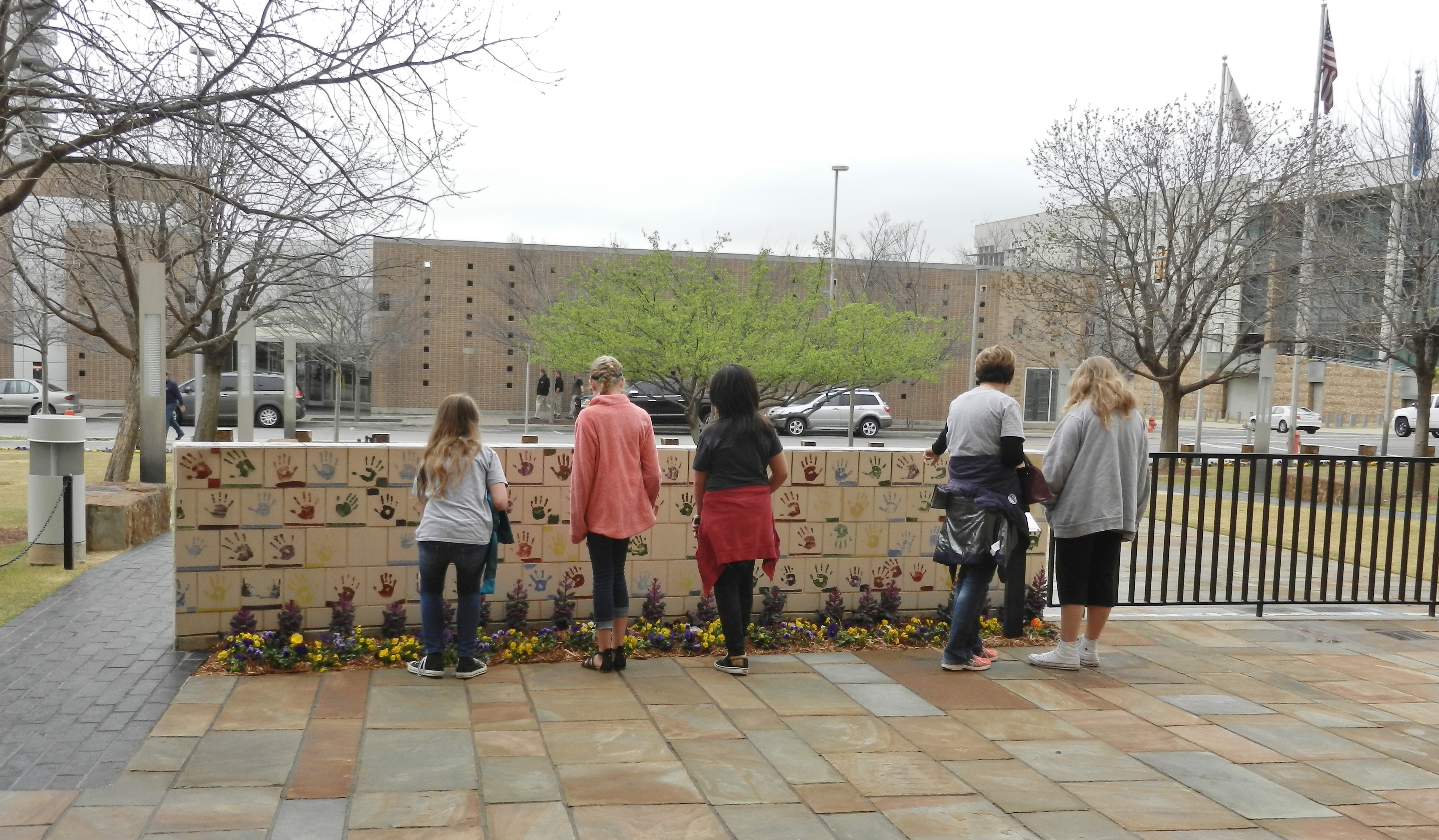 children and adults visiting a wall decorated with handprints