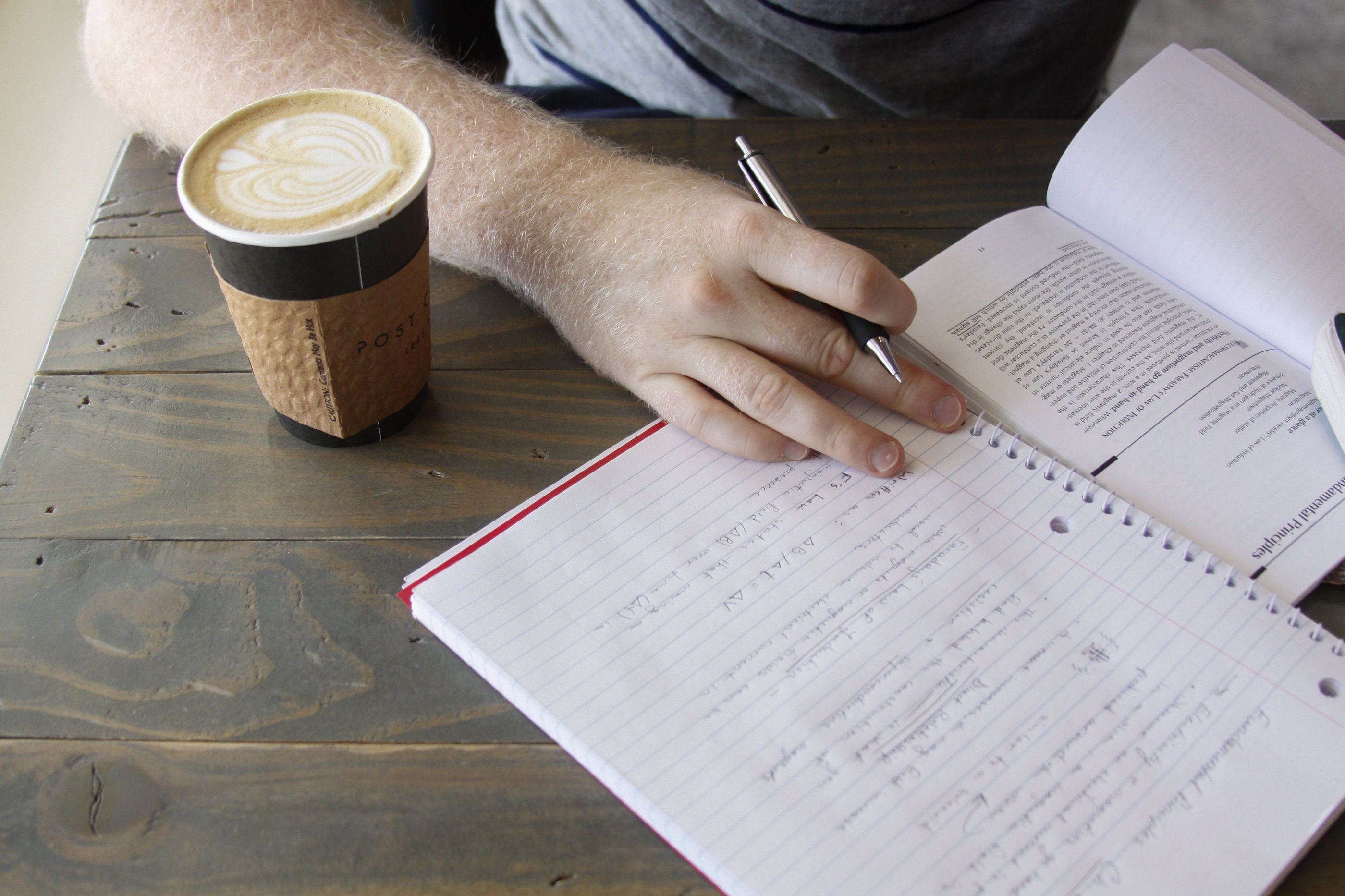 person writing in a spiral notebook