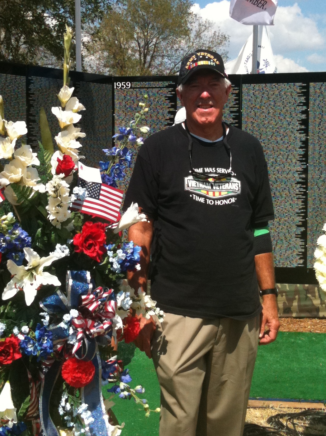 army veteran standing next to a floral bouquet at a memorial