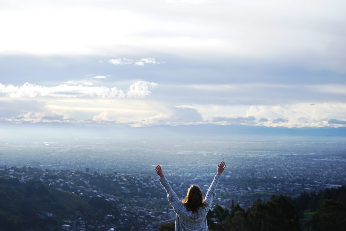 woman standing with arms lifted to the sky