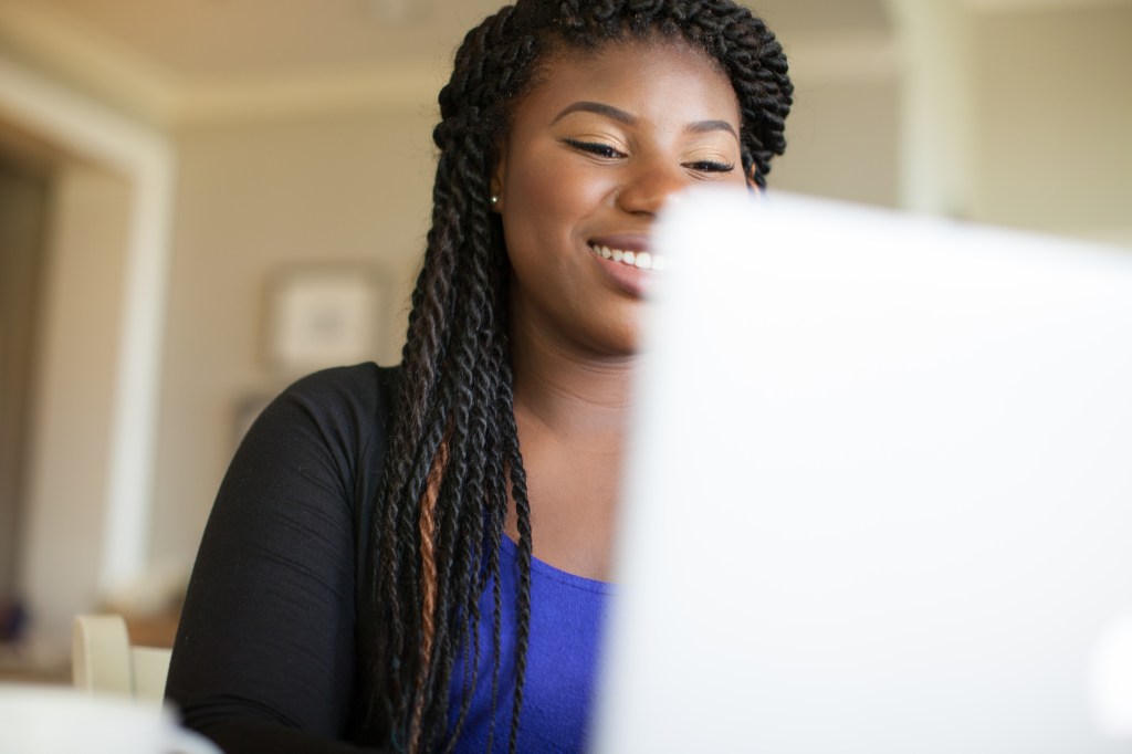 a smiling woman working on a laptop computer