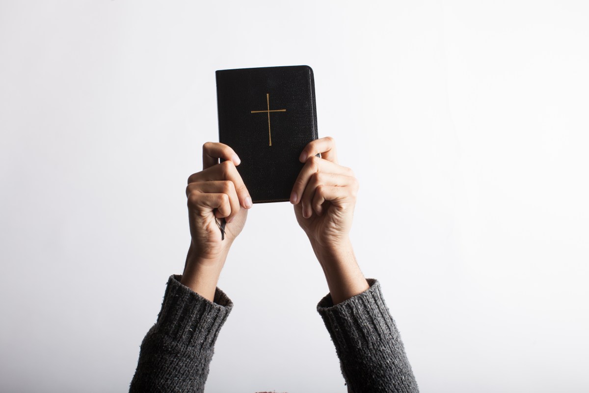 a Bible held up with two hands by unknown person