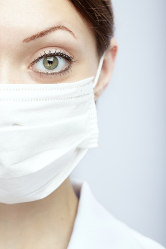 a woman in white coat with mask over mouth