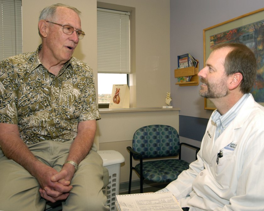 Michael Munger, M.D., consults a patient at his medical office in Overland Park, Kan.