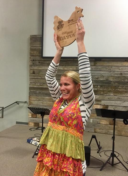 woman in an apron holding a wooden sign-