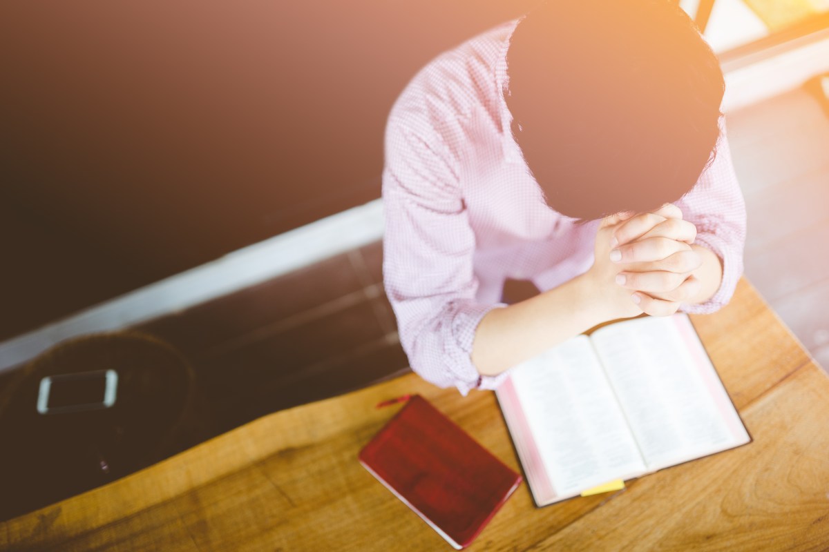 man praying on holy bible in the morning