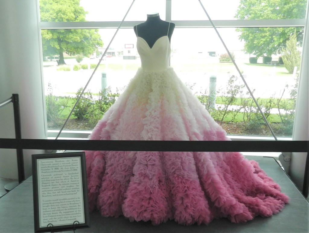 a floor length, fancy pink and white dress covered in ruffles on the skirt