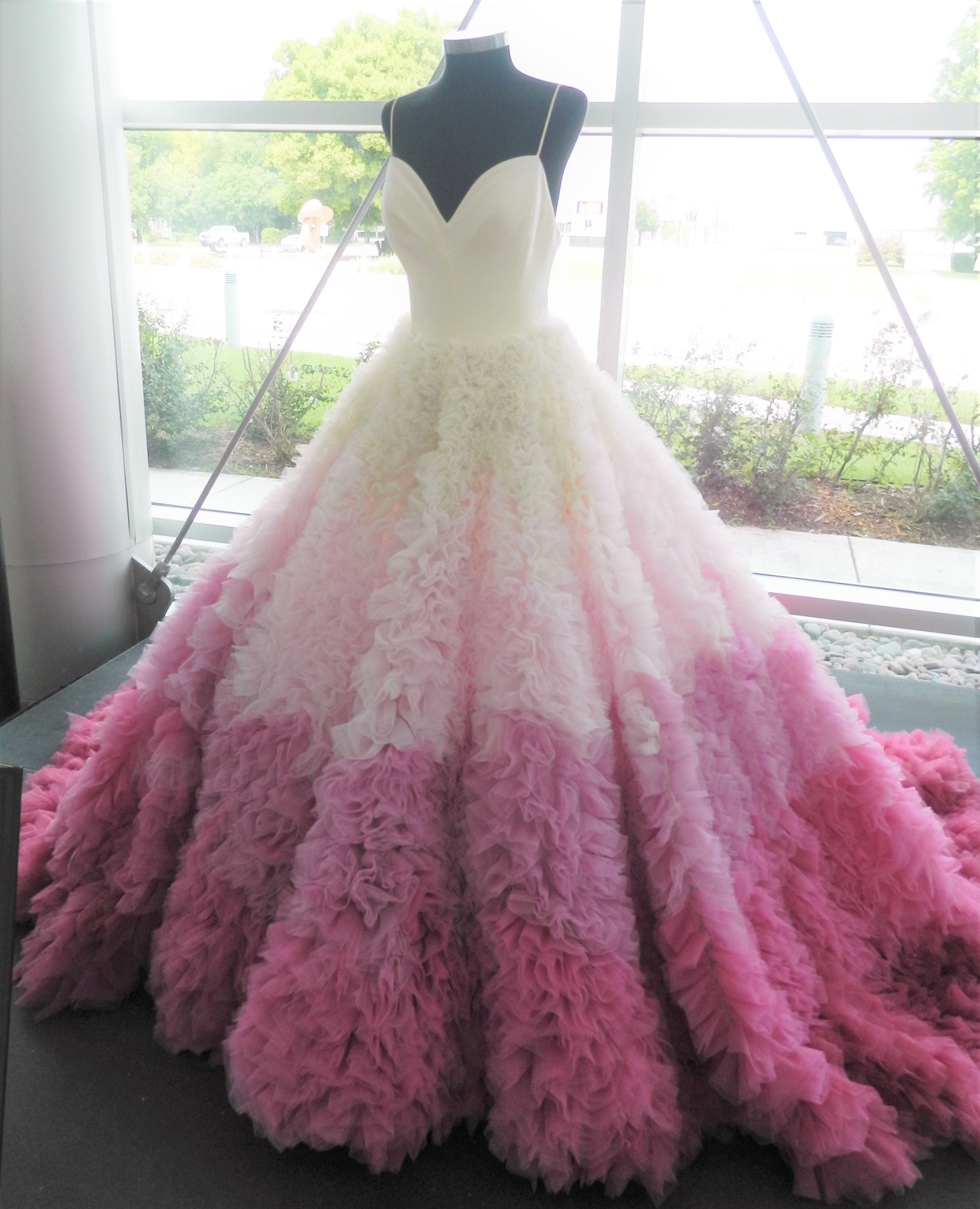 a floor length, fancy pink and white dress covered in ruffles on the skirt