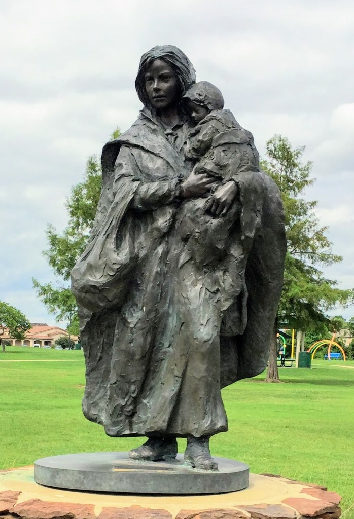 a bronze statue of a woman holding a small child