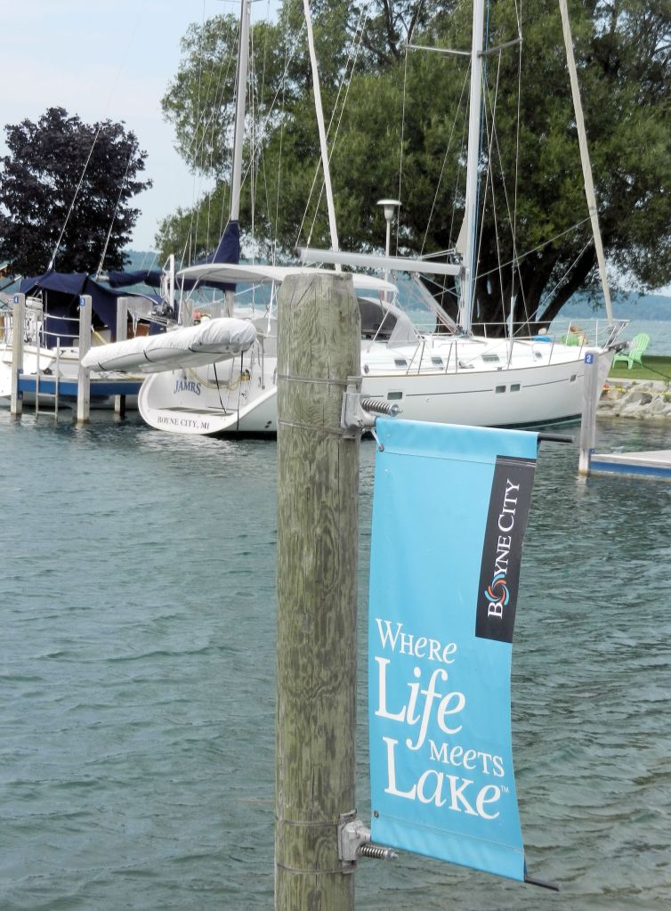 a boat tied at a dock, a sign reads "where life meets lake"