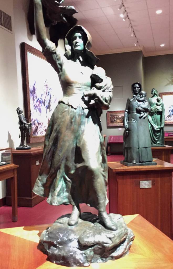 statue of woman with arm raised and holding an infant