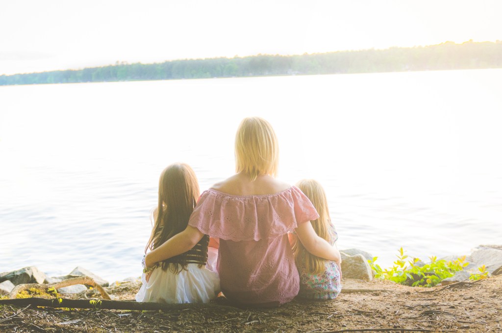 a woman with her arms around 2 little girls on each side