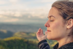 upclose view of a woman with eyes closed, arms outstretched, looks peaceful