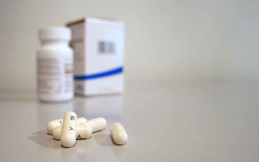 white capsules in front of a prescription bottle