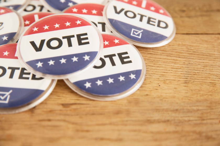 a group of lapel buttons, red, white and blue, saying VOTE
