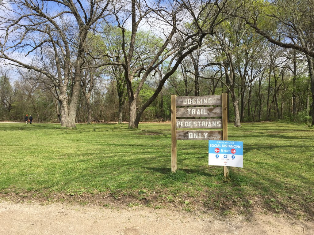 a walking trail at a park, sign advised social distancing