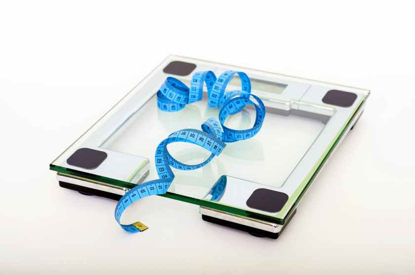 blue tape measure lying on clear glass square weighing scale