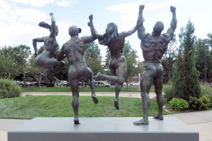 bronze statues of 4 athletes, arms raised, 2 jumping up