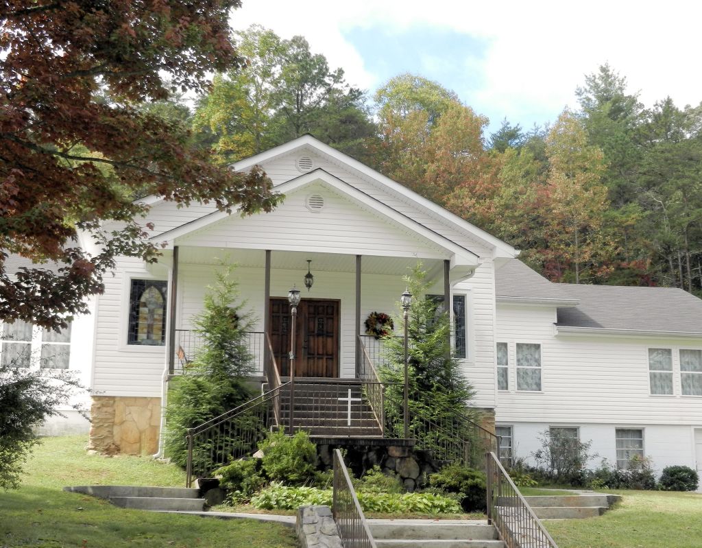 a simple white church flanked by autumn trees
