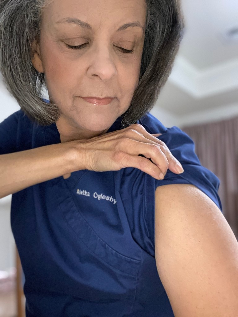 Dr. Aletha inspecting her arm after a COVID-19 shot