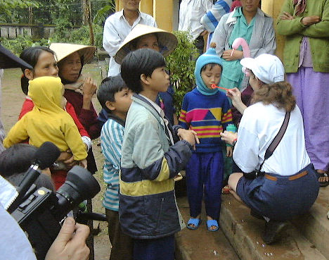 Vietnamese children with an American woman, blowing bubbles