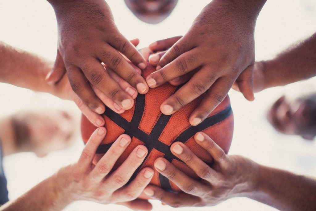 the hands of several people holding a basketball