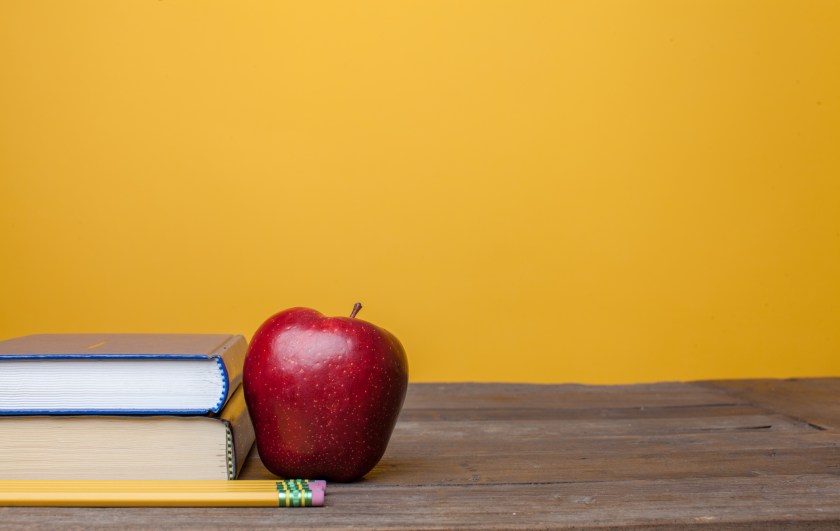 2 books stacked next to an apple l