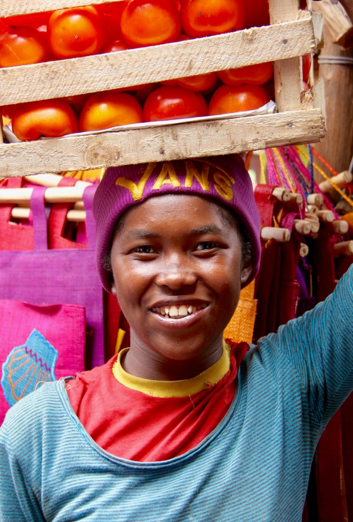 A young African woman with a crate of tomatoes on her head