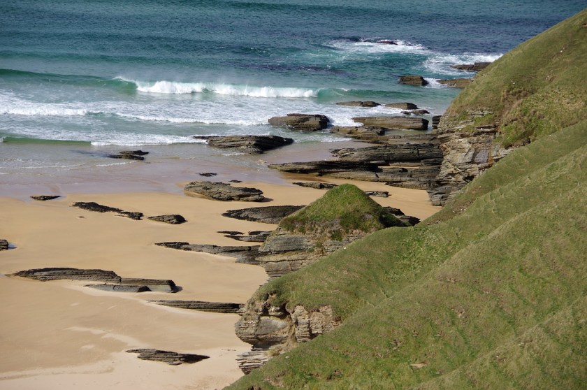 a sandy rocky beach with crashing waves of turquois water