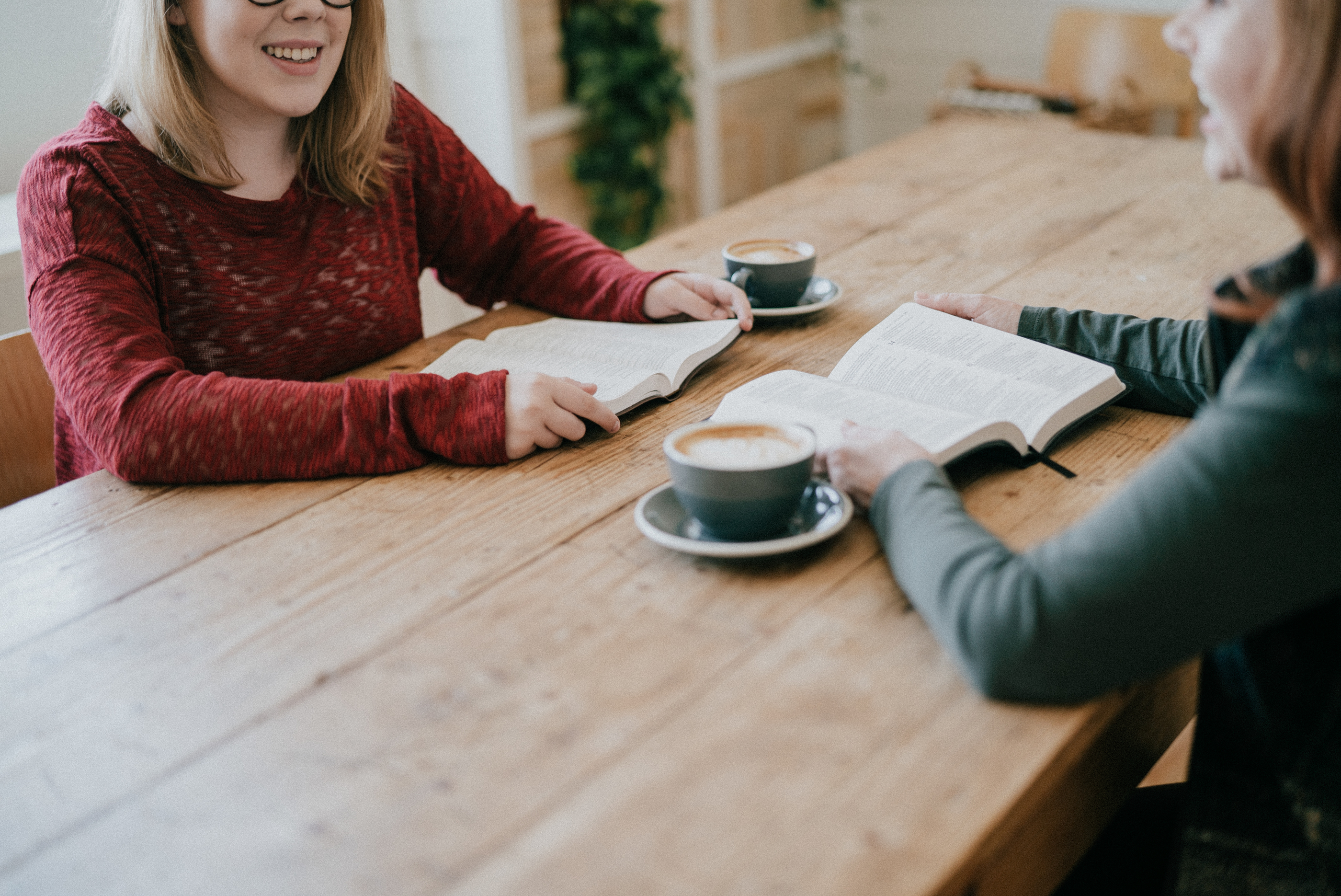 two women, talking, sitting across a table, with coffee and open Bibles