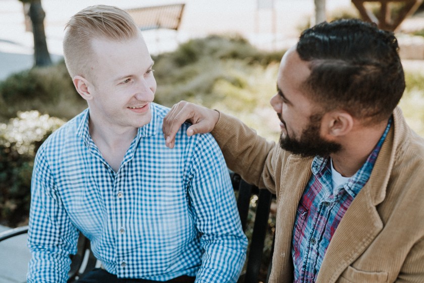 2 young men, one white, one black, talking, smiling