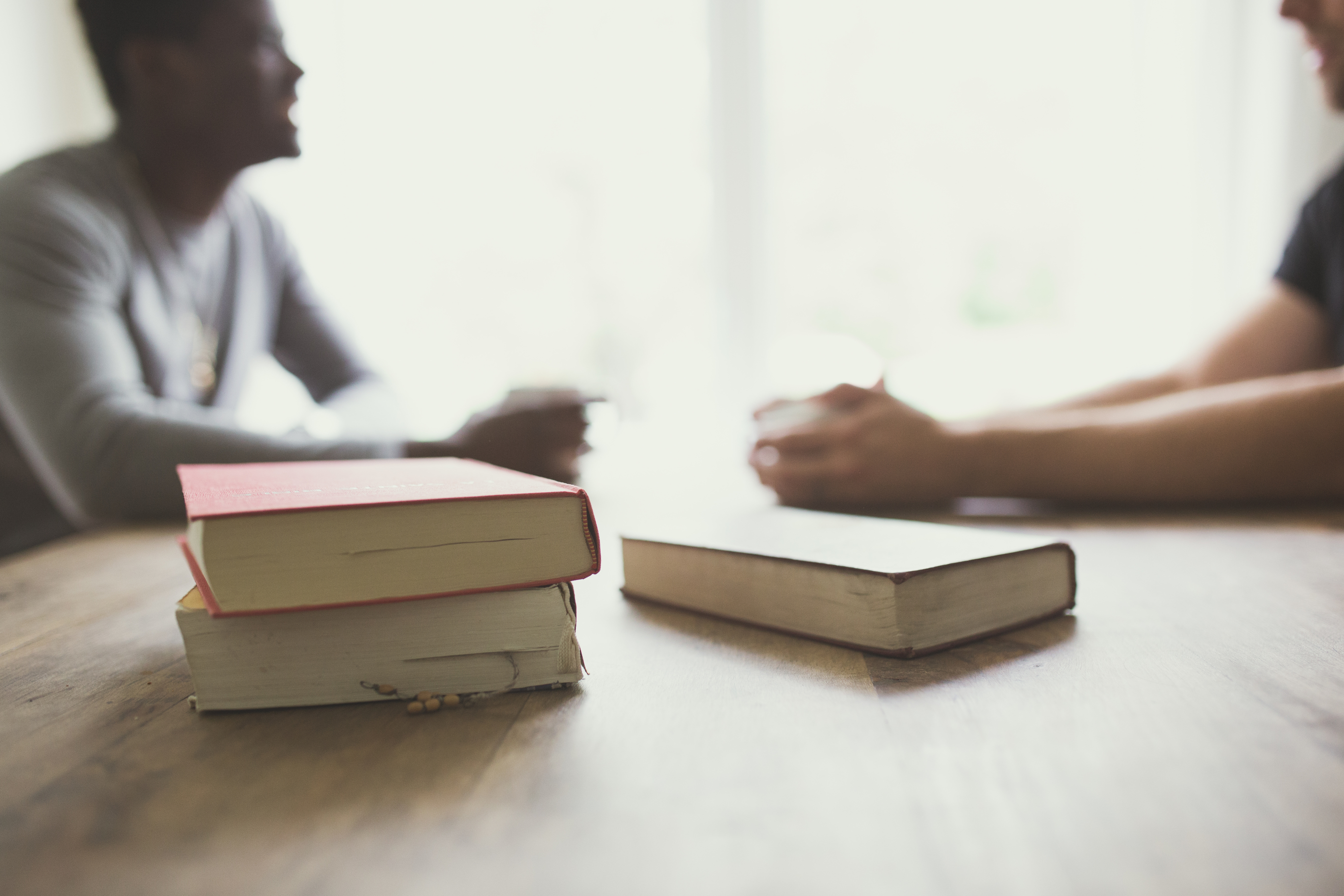 two males talking, books on a table beside them