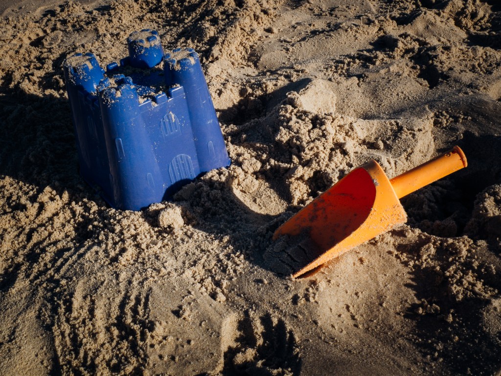 a toy castle and shovel in the sand