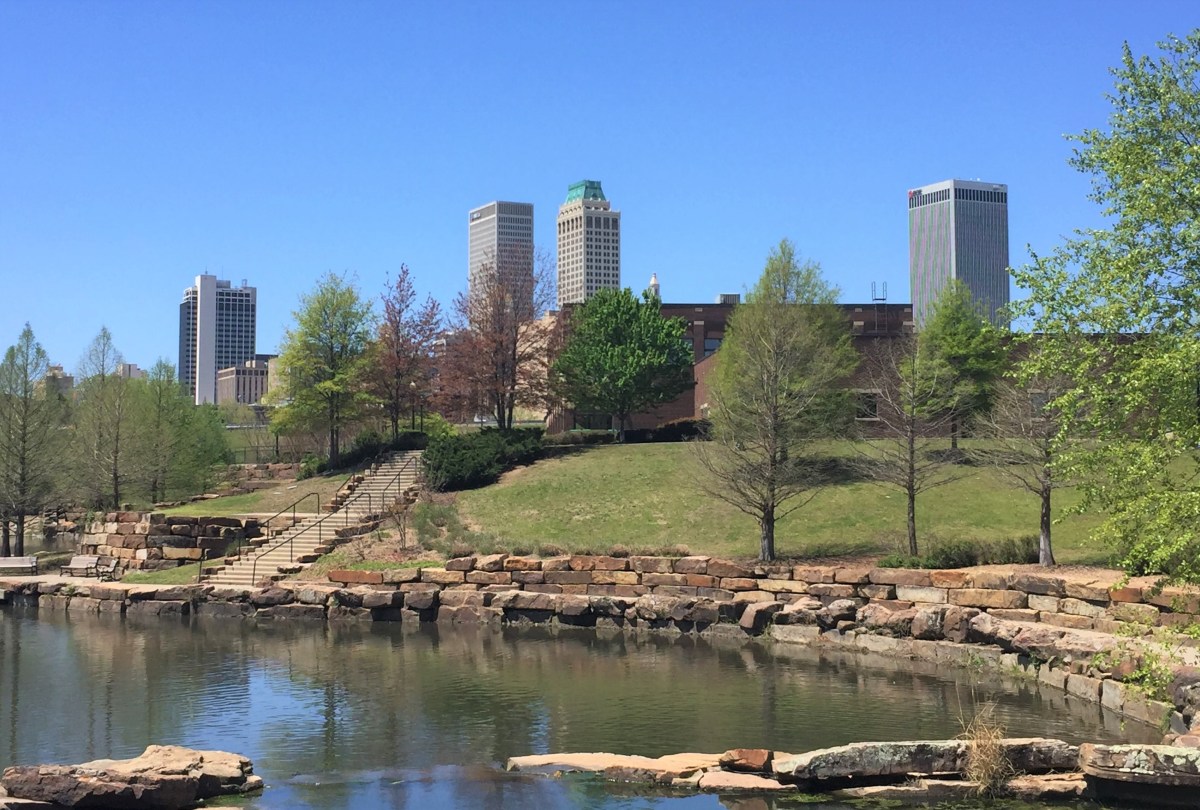 a pond in a park with skyscrapers in the distance