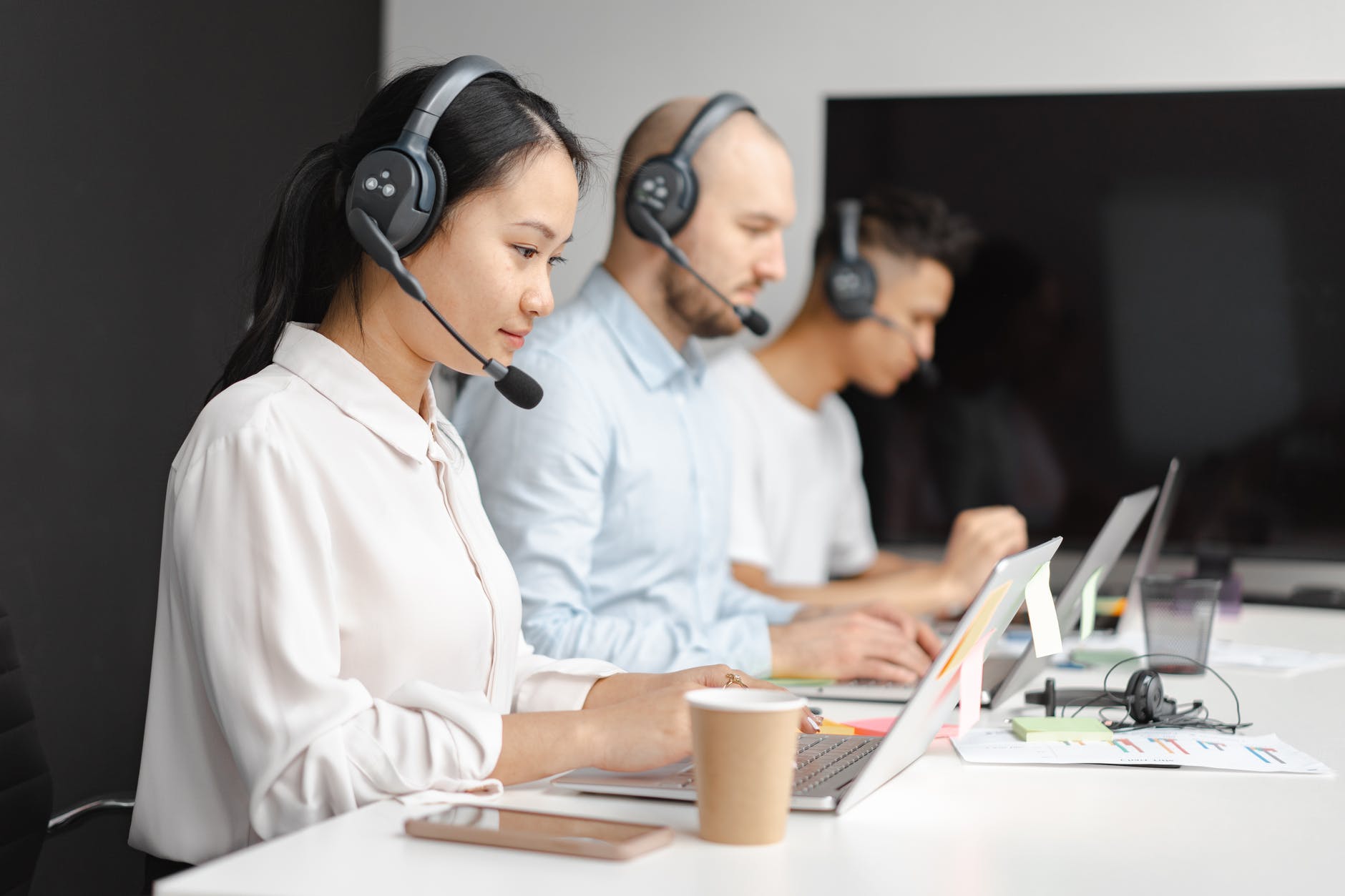 shallow focus of woman and 2 men working in a call center