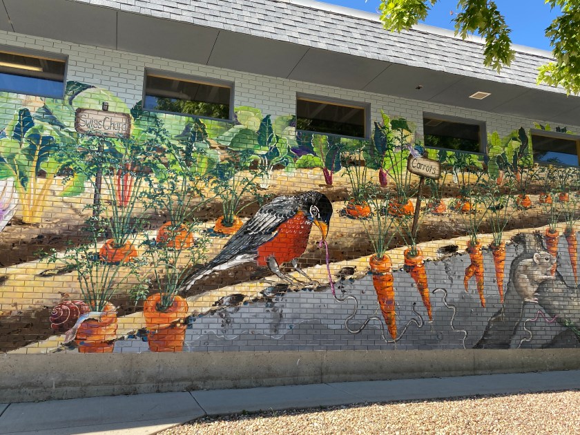 a red and black bird painted on a brick building