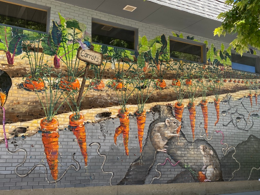 2 mice eating carrots in a garden-painted on a brick wall