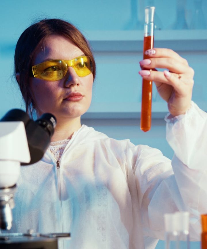 a woman holding while looking at a test tube